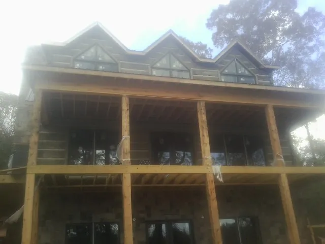 Dormers and porch framing on a large log home under construction — Roof Coating work by our crew in Sweet Springs