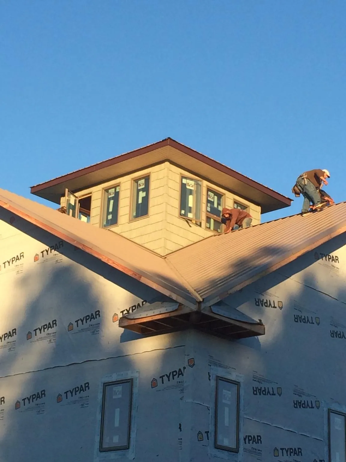 Roofers working around a rooftop cupola on a new metal roof at sunset — Roof Waterproofing in Sweet Springs by Roofing Brothers